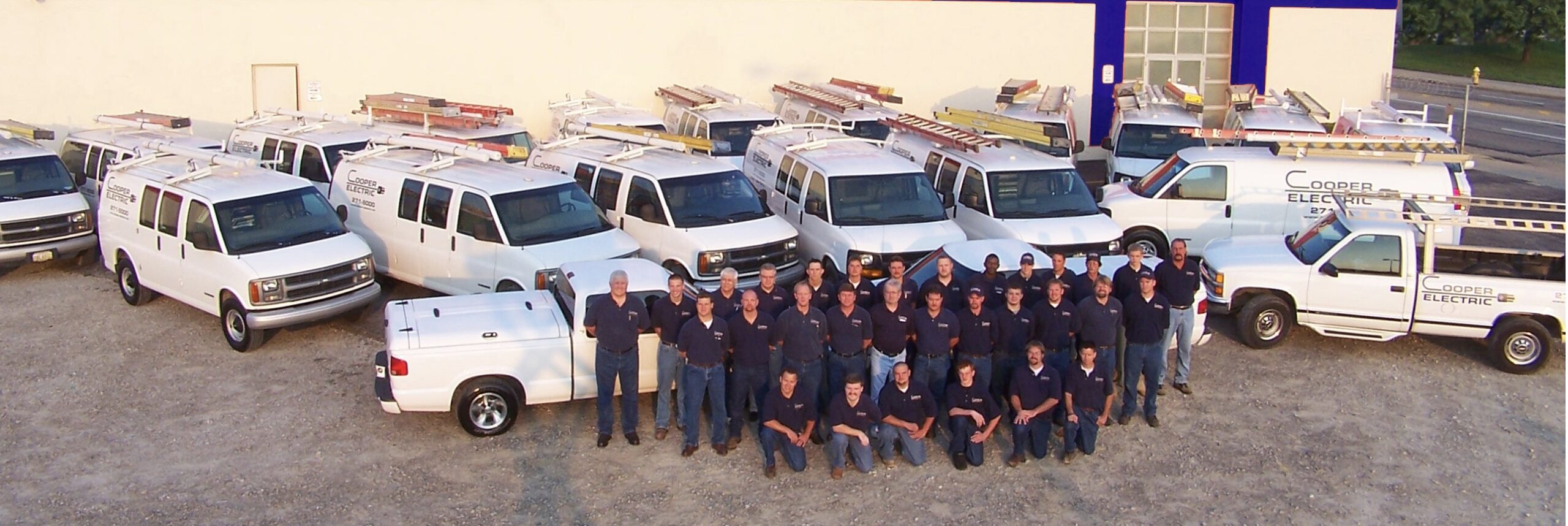 The Cooper Electric team standing with the company fleet of service trucks and vans